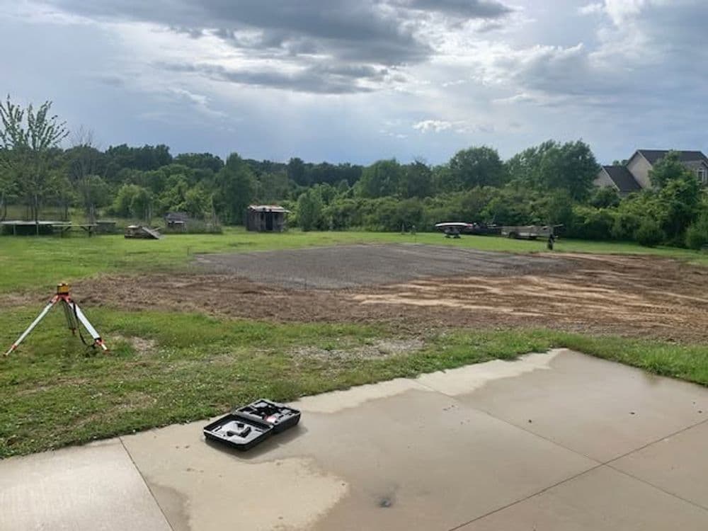 Cleared land for construction with surveying equipment and a cloudy sky in the background.